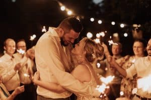 Glückliches Brautpaar wird von den Hochzeitsgästen mit Wunderkerzen verabschiedet